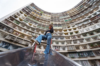 Low angle view of woman standing against building in city