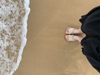 Low section of woman standing at beach