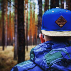 Rear view of man wearing mask against trees in forest