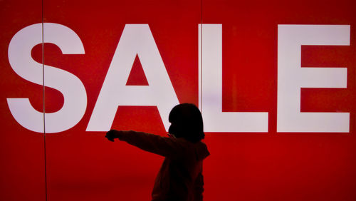 Silhouette girl against illuminated wall with text