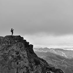 Man standing on rock against sky