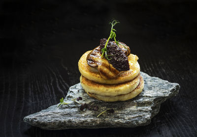 Close-up of pancakes with fried foie gras and onion marmalade on stone at table