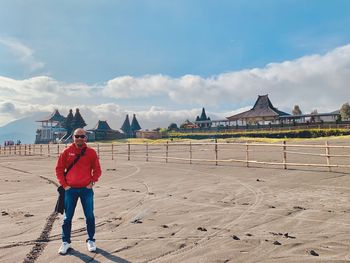 Full length of man standing on street against sky