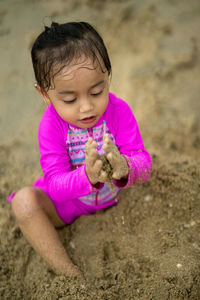 High angle view of cute girl playing with sand at beach