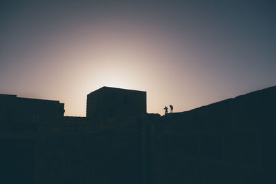 Low angle view of silhouette buildings against clear sky