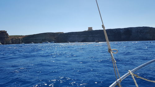 Sailboat sailing on sea against clear blue sky