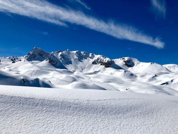 Scenic view of snowcapped mountains against blue sky