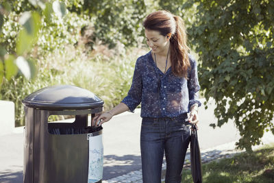 Businesswoman throwing garbage in bin at park