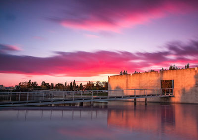 River by buildings against sky at sunset