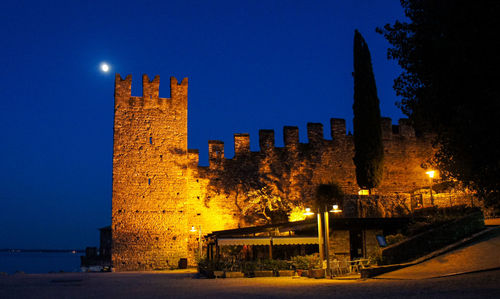 Illuminated buildings against clear sky at night