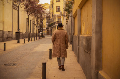 Rear view of man in hat and coat on street during sand storm day. madrid, spain