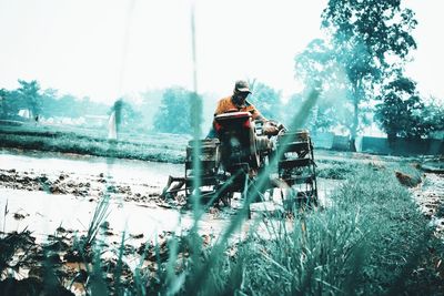 Rear view of man riding motorcycle on field