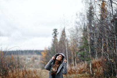 Woman standing on field against trees during winter