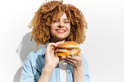 Portrait of smiling young woman holding apple against white background