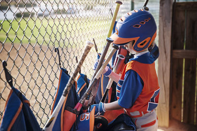 Side view of boy removing baseball bat from bag at field