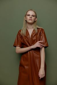 Portrait of young woman standing against wall
