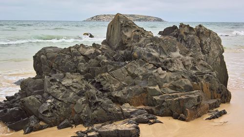 Rock formation on beach against sky