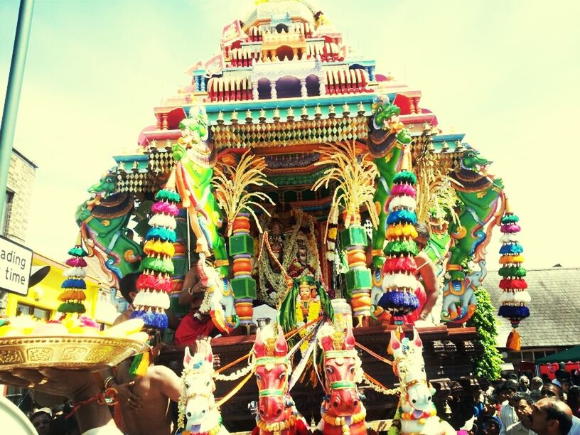 low angle view, multi colored, architecture, built structure, art and craft, sky, building exterior, art, amusement park, creativity, day, outdoors, cultures, amusement park ride, arts culture and entertainment, human representation, tradition, incidental people, decoration, in a row