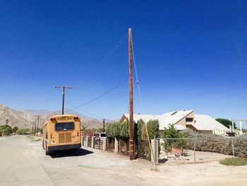 School bus parked on road against clear blue sky