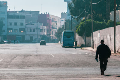 Rear view of man walking on road in city