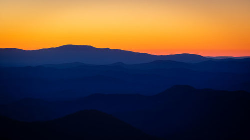 Scenic view of silhouette mountains against orange sky