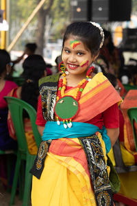 An indian girl child with colorful face in holi looking at camera