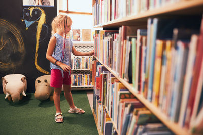 Schoolgirl looking for books in school library. elementary education. back to school