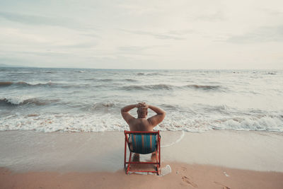 Rear view of person on beach against sky