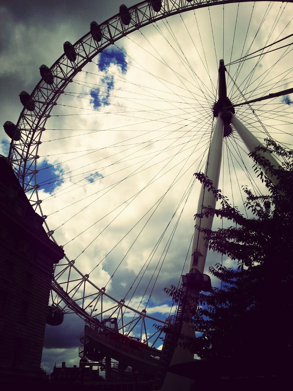 low angle view, amusement park, ferris wheel, amusement park ride, sky, arts culture and entertainment, silhouette, built structure, architecture, cloud - sky, connection, power line, dusk, cloud, outdoors, electricity pylon, cloudy, sunset, cable, no people