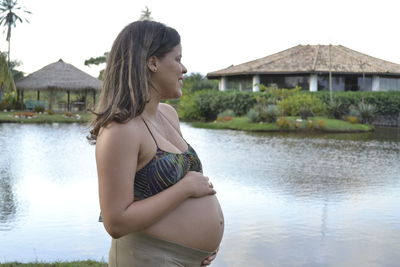 Pregnant woman standing at lake against sky