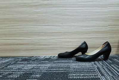 Low section of black shoes on floor