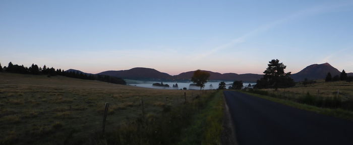 Road leading towards mountains against clear sky