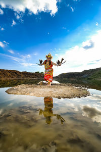 Reflection of person standing in water against sky