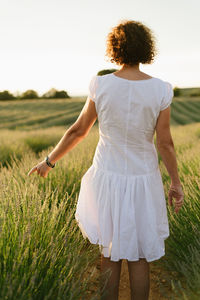 Rear view of woman with arms outstretched on field