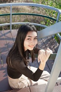 Portrait of woman sitting on railing