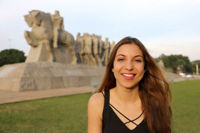 Portrait of smiling young woman against sculpture