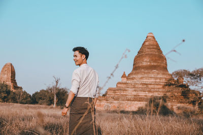 Rear view of young man standing by built structure