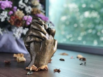 Sculpture of hands with dried petals on table