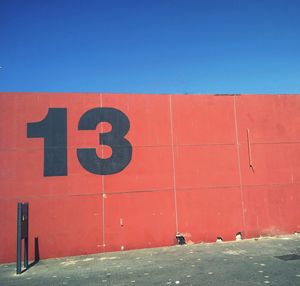 Number 13 on red wall against blue sky