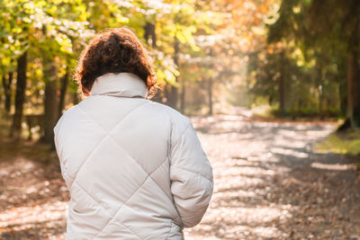 Woman with her back to the camera in an autumn forest trail.