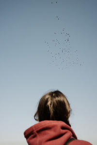 Rear view of woman flying against clear sky