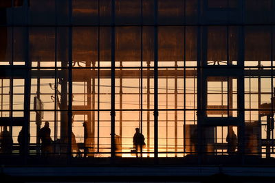 Silhouette people on glass window of building