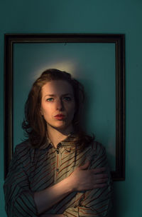 Mid adult woman standing against picture frame on wall