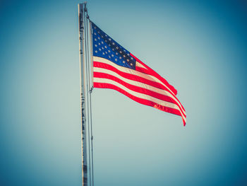 Low angle view of flag against clear blue sky