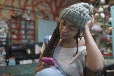 Young woman using smartphone while sitting in kitchen