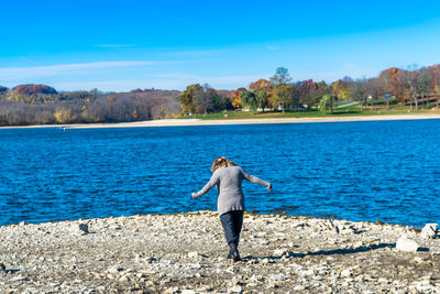 Rear view of woman on beach against blue sky