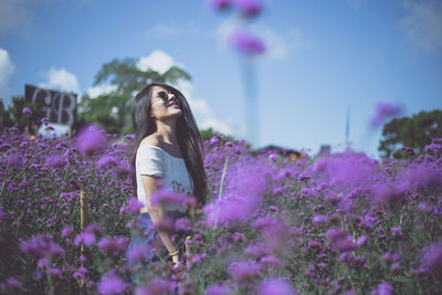 Woman standing on pink flowering plants on field