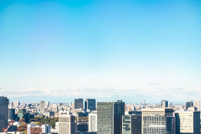 Buildings in city against clear blue sky