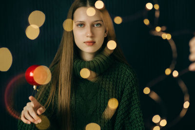 Beautiful teenager girl twists christmas red ball on her finger