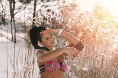 Side view of young woman standing against plants